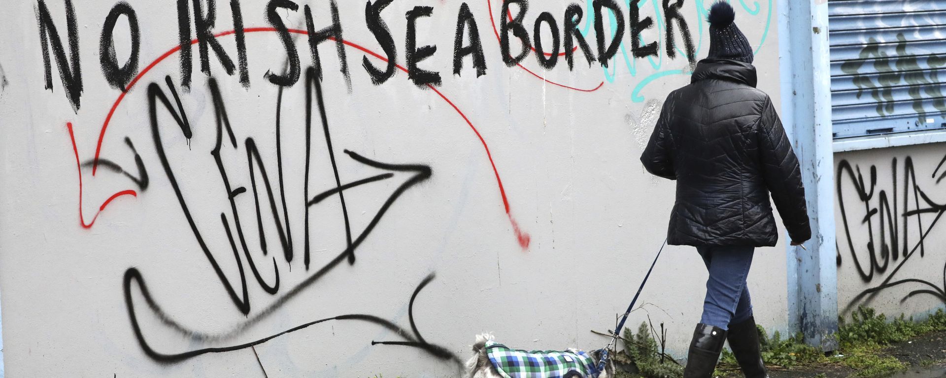 A woman walks her dog past past graffiti with the words 'No Irish Sea Border' in Belfast city centre, Northern Ireland, Wednesday, Feb. 3, 2021 A woman walks her dog past past graffiti with the words 'No Irish Sea Border' in Belfast city centre, Northern Ireland, Wednesday, Feb. 3, 2021 - Sputnik International, 1920, 08.04.2021