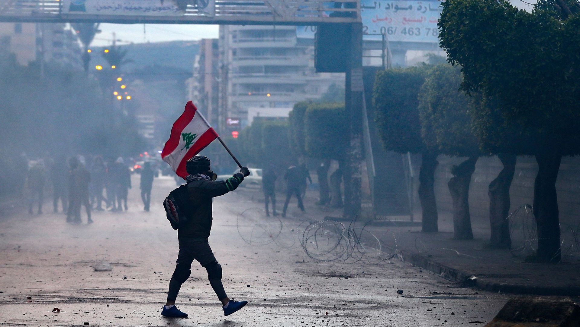 A Lebanese anti-government protester waves a national flag during clashes with security forces in front of the Serail (headquarters of the Governorate), in the northern port city of Tripoli, following a demonstration to protest against the economic situation, on January 28, 2021. A Lebanese anti-government protester waves a national flag during clashes with security forces in front of the Serail (headquarters of the Governorate), in the northern port city of Tripoli, following a demonstration to protest against the economic situation, on January 28, 2021. - Sputnik International, 1920, 08.03.2021