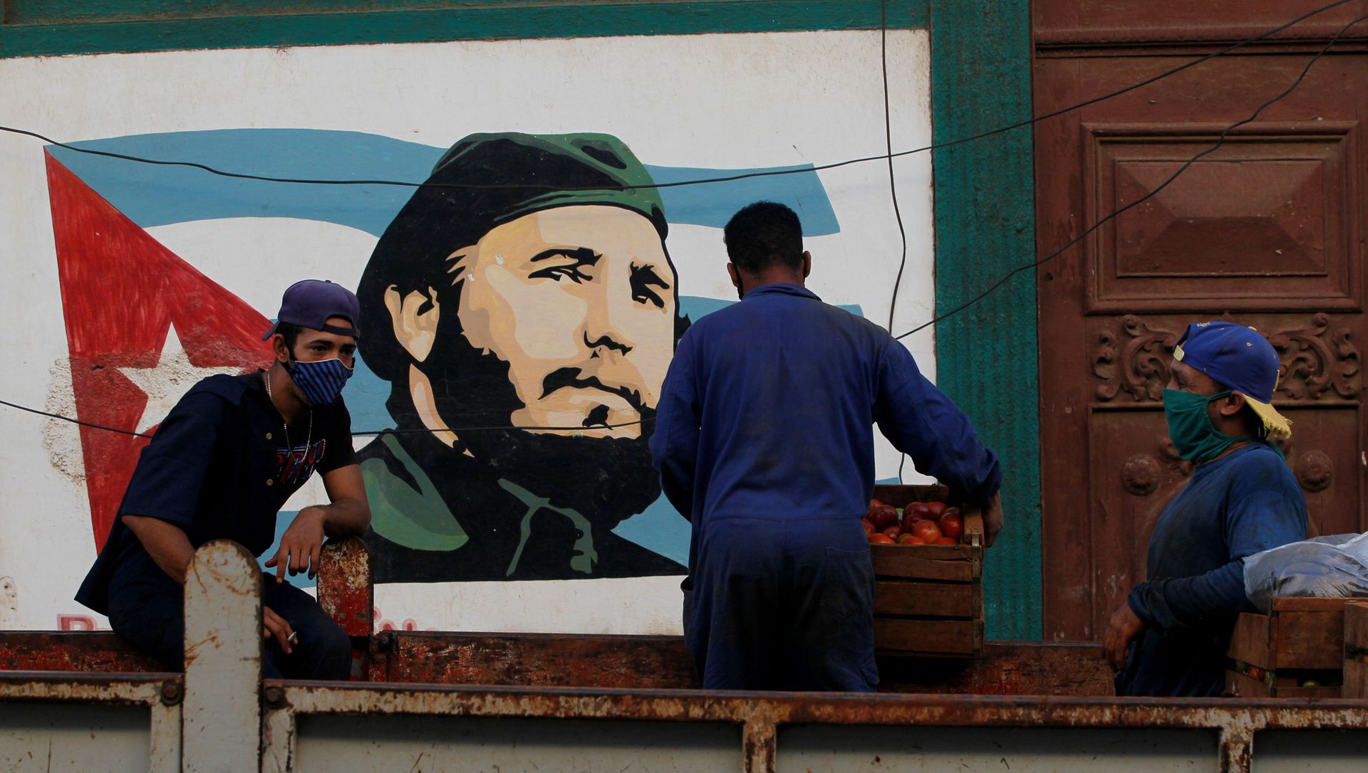 Workers stand on the back of a truck next to an image of late Cuban leader Fidel Castro, in Havana Workers stand on the back of a truck next to an image of late Cuban leader Fidel Castro, in Havana - Sputnik International, 1920, 22.02.2021