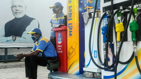 Employees of a petrol station wait for customers near a poster of India's Prime Minister Narendra Modi (L) during a new lockdown imposed by the state government against the surge in COVID-19 coronavirus cases, in Kolkata on 29 July 2020. - Sputnik International