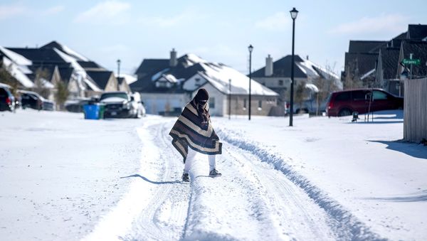 A man walks to his friend's home in a neighbourhood without electricity as snow covers the BlackHawk neighborhood in Pflugerville, Texas, U.S. February 15, 2021. Picture taken February 15, 2021.  - Sputnik International