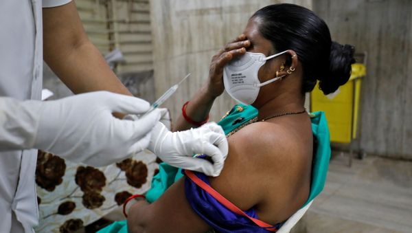 A healthcare worker reacts as she receives the second dose of COVISHIELD, a COVID-19 vaccine manufactured by Serum Institute of India, at a hospital in Ahmedabad, India, February 15, 2021 - Sputnik International