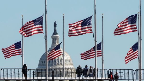 People walk past flags flying at half staff at the Washington Monument in memory of 500,000 deaths due to the coronavirus disease (COVID-19) in Washington, U.S., February 24, 2021.    - Sputnik International