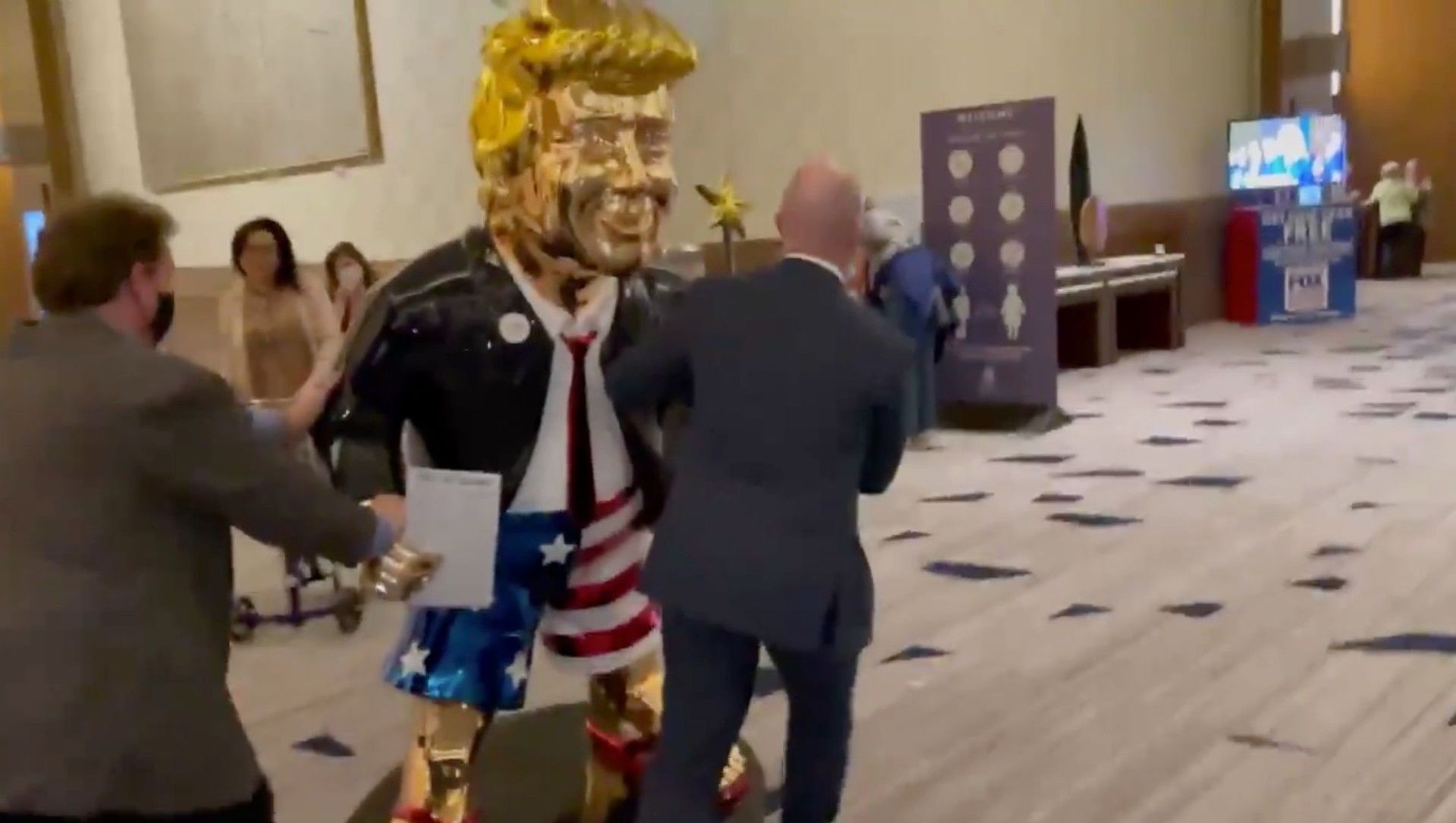 Screenshot captures golden statue of former US President Donald Trump being wheeled toward an event associated with the annual Conservative Police Action Conference. Screenshot captures golden statue of former US President Donald Trump being wheeled toward an event associated with the annual Conservative Police Action Conference. - Sputnik International, 1920, 26.02.2021