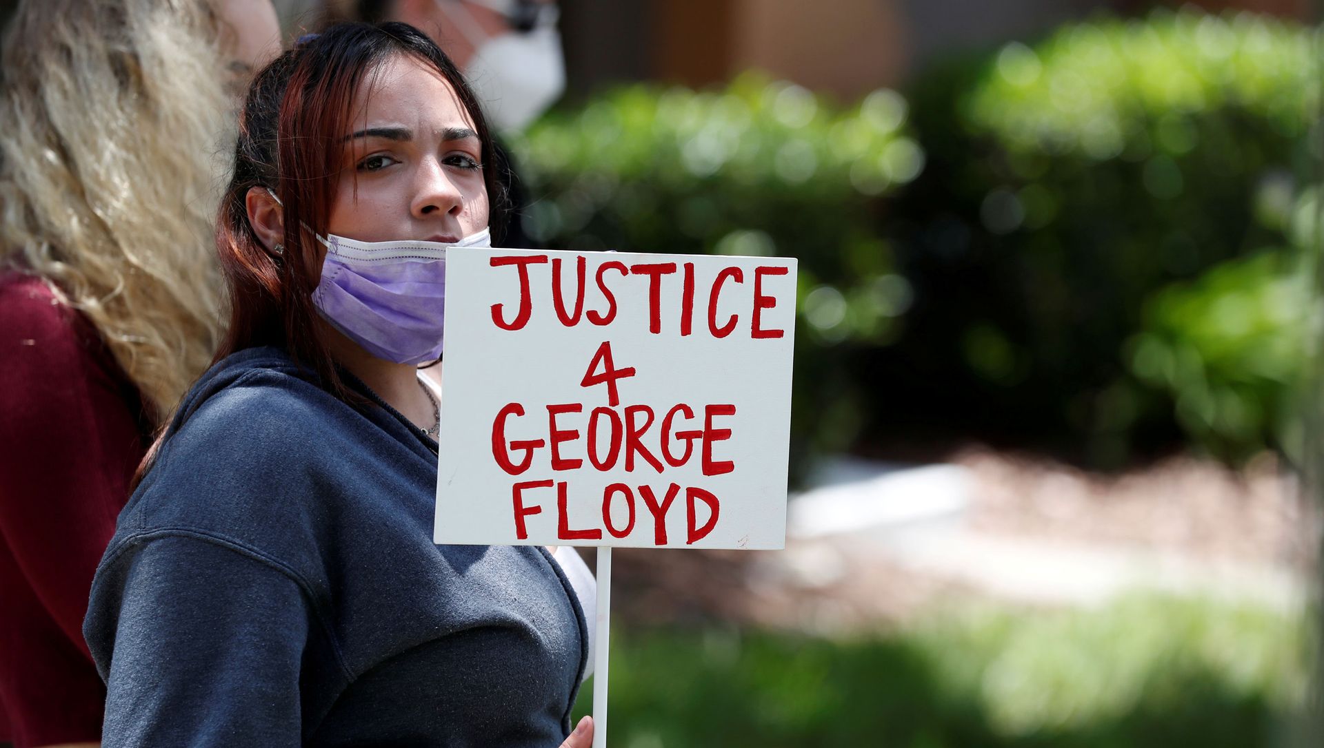 A protester holds a sign outside the Florida home of former Minneapolis police officer Derek Chauvin, who was recorded with his knee on the neck of African-American man George Floyd A protester holds a sign outside the Florida home of former Minneapolis police officer Derek Chauvin, who was recorded with his knee on the neck of African-American man George Floyd - Sputnik International, 1920, 08.03.2021