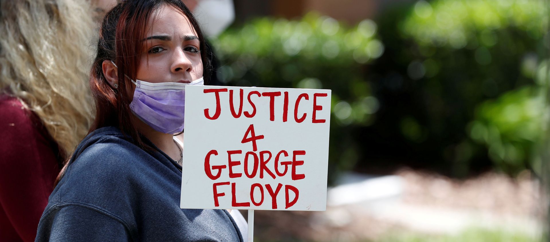 A protester holds a sign outside the Florida home of former Minneapolis police officer Derek Chauvin, who was recorded with his knee on the neck of African-American man George Floyd - Sputnik International, 1920, 08.03.2021