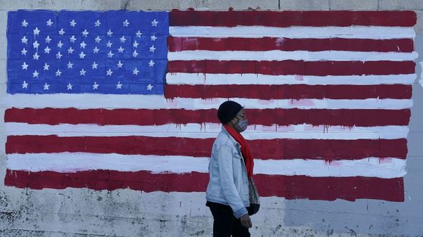 In this Nov. 16, 2020, file photo, a woman wears a mask while walking past an American flag painted on a wall during the coronavirus outbreak in San Francisco. In this Nov. 16, 2020, file photo, a woman wears a mask while walking past an American flag painted on a wall during the coronavirus outbreak in San Francisco. - Sputnik International
