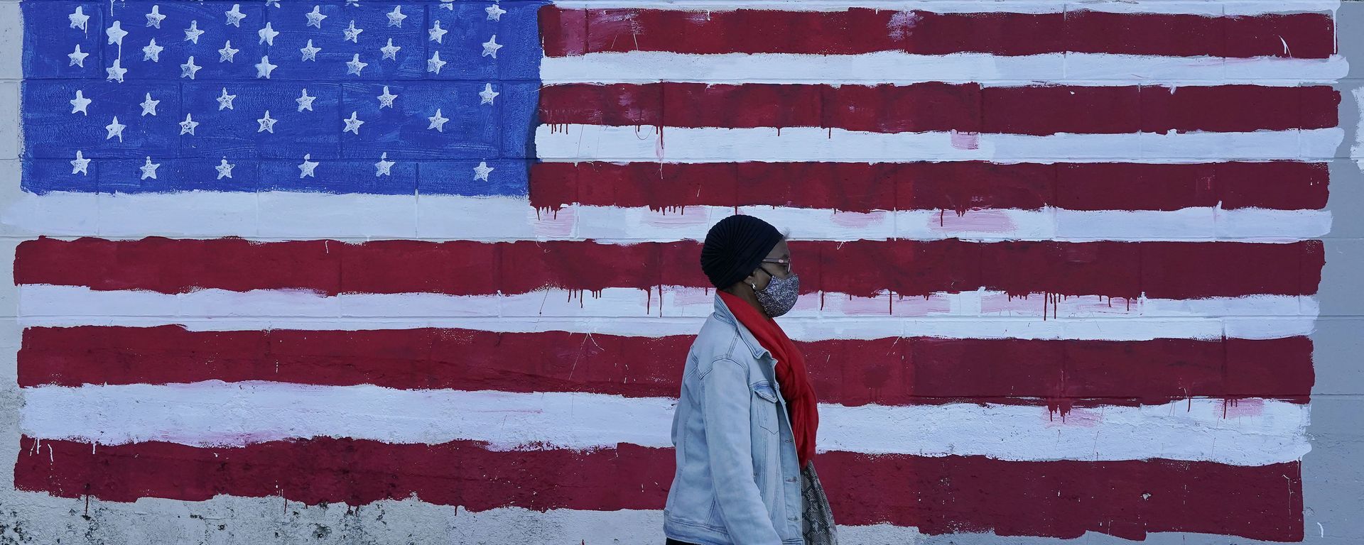 In this Nov. 16, 2020, file photo, a woman wears a mask while walking past an American flag painted on a wall during the coronavirus outbreak in San Francisco. - Sputnik International, 1920, 28.03.2023