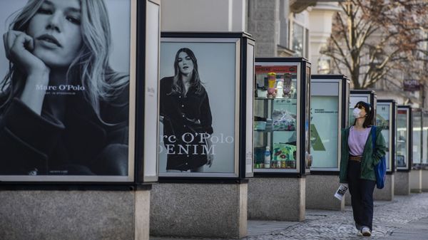 A woman wearing a face mask walks by advertising booths on Berlin's Kurfuerstendamm shopping mile on March 3, 2021, during the ongoing coronavirus (Covid-19) pandemic. - Sputnik International