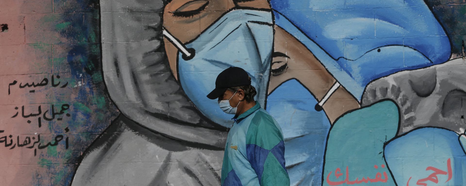 A Palestinian man walks past street art showing doctors mask-clad due to the COVID-19 coronavirus pandemic in the Nusseirat refugee camp in the central Gaza Strip on November 16, 2020. A Palestinian man walks past street art showing doctors mask-clad due to the COVID-19 coronavirus pandemic in the Nusseirat refugee camp in the central Gaza Strip on November 16, 2020. - Sputnik International, 1920, 16.04.2021