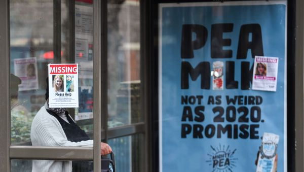 A person sits at a bus stop next to signs that show pictures of Sarah Everard, who disappeared last week, as police continue to search parts of Clapham, in London, Britain, March 10, 2021 - Sputnik International