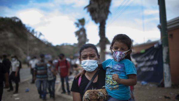 A woman and a girl walk away as Honduran migrants confront Guatemalan soldiers and police blocking them from advancing toward the US, on the highway in Vado Hondo, Guatemala, Monday, Jan. 18, 2021. The roadblock was strategically placed at a chokepoint on the two-lane highway flanked by a tall mountainside and a wall leaving the migrants with few options. - Sputnik International