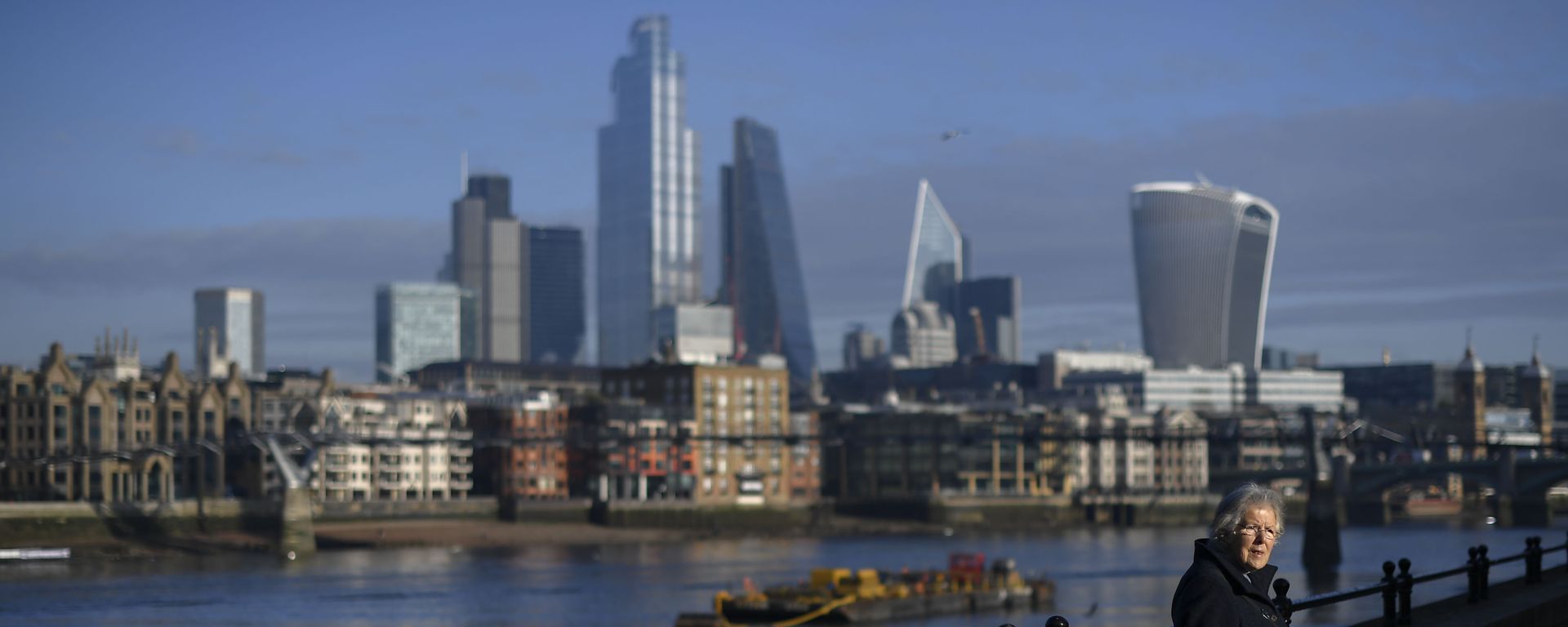 A woman rests in the sunshine on the south bank of River Thames with the skyline of the financial district called 'the City' in the background, in London, Tuesday, Dec. 8, 2020 - Sputnik International, 1920, 02.05.2023