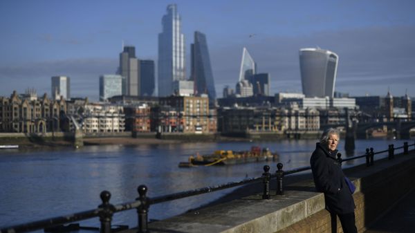 A woman rests in the sunshine on the south bank of River Thames with the skyline of the financial district called 'the City' in the background, in London, Tuesday, Dec. 8, 2020 - Sputnik International