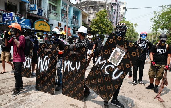 Demonstrators stand behind makeshift shields during an anti-coup protest in Yangon - Sputnik International