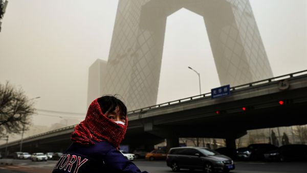 A woman wearing a head covering is seen in front of the headquarters of China's state media broadcaster CCTV that is shrouded in a haze after a sandstorm in the Central Business District of Beijing, China. - Sputnik International