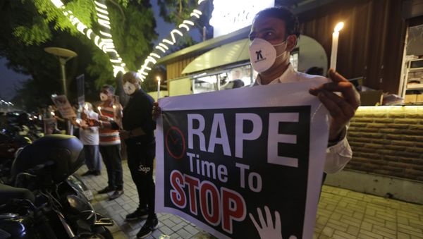 A man holds a poster  and candle during a protest against the alleged gang rape and killing of a Dalit woman, in Ahmedabad, India, Tuesday, Oct. 6, 2020 - Sputnik International