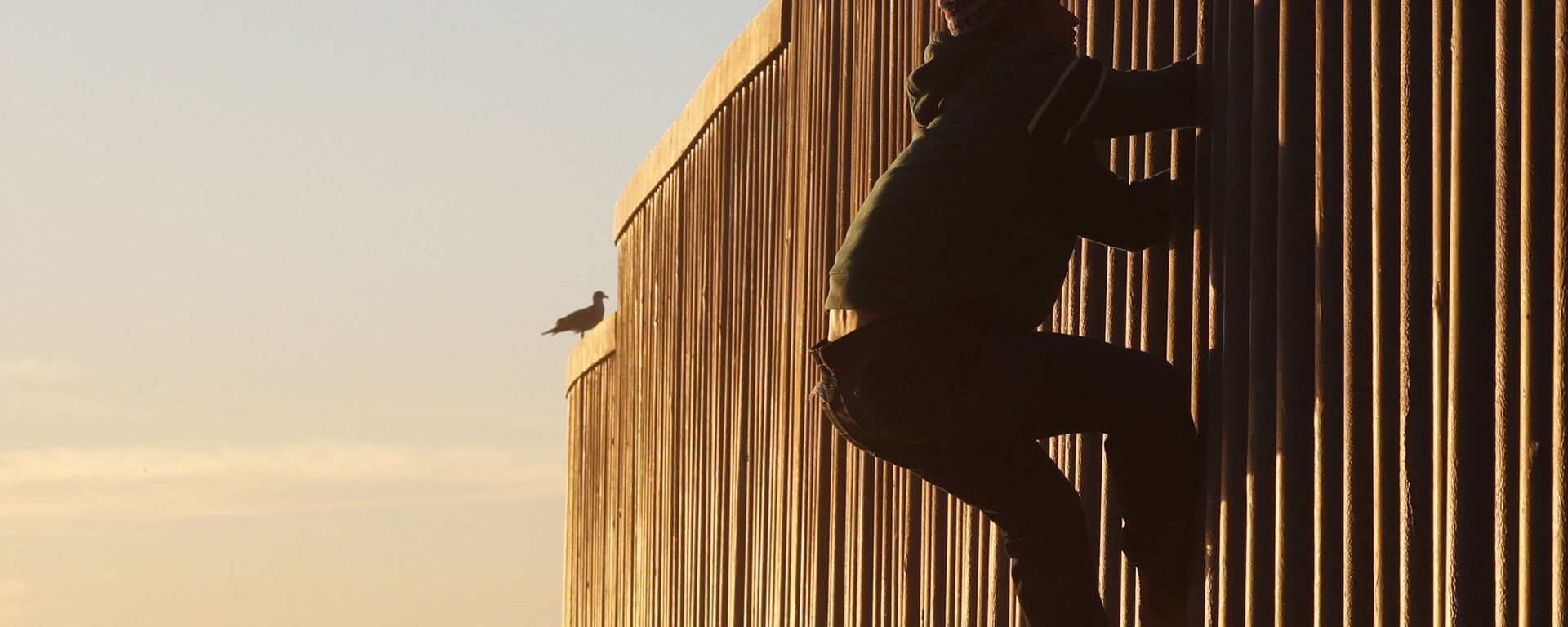 Honduran migrant Jonatan Matamoros Flores, 33, who arrived in October with a migrant caravan, climbs the U.S. border wall to stand atop it before returning to the Mexican side in Tijuana, Mexico, Saturday, Dec. 8, 2018 Honduran migrant Jonatan Matamoros Flores, 33, who arrived in October with a migrant caravan, climbs the U.S. border wall to stand atop it before returning to the Mexican side in Tijuana, Mexico, Saturday, Dec. 8, 2018 - Sputnik International, 1920, 16.03.2021