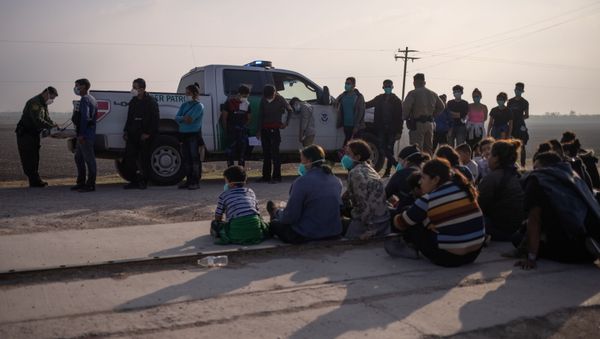 A U.S. Border Patrol agent processes asylum-seeking unaccompanied minors as family units sit on the sideline after about 70 migrants crossed the Rio Grande river into the United States from Mexico on a raft in Penitas, Texas, U.S., March 17, 2021. - Sputnik International