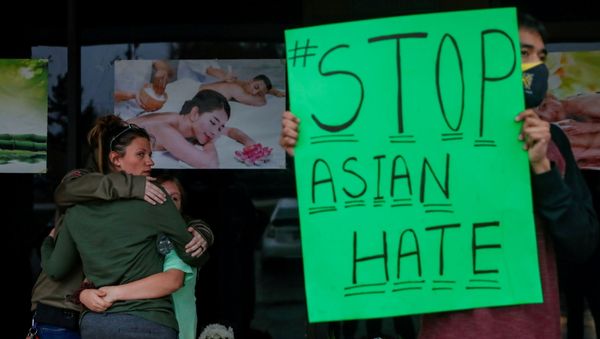 People grieve as Jesus Estrella, 21 holds a sign outside Young's Asian Massage after the deadly shootings in Acworth, Georgia, US 17 March 2021. REUTERS/Shannon Stapleton  - Sputnik International