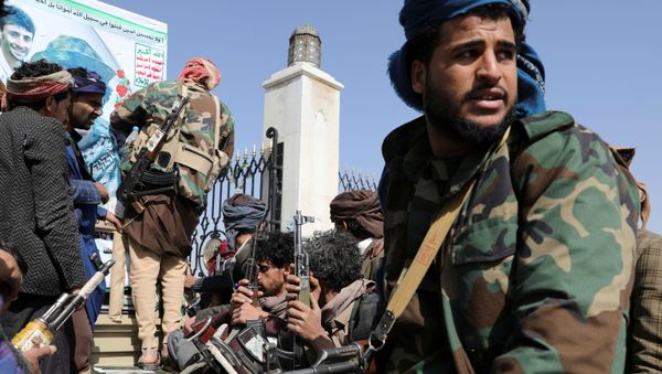 Armed Houthi followers sit next to a coffin of a Houthi fighter killed in recent fighting against government forces in Yemen's oil-rich province of Marib, during a funeral procession in Sanaa, Yemen February 20, 2021. - Sputnik International