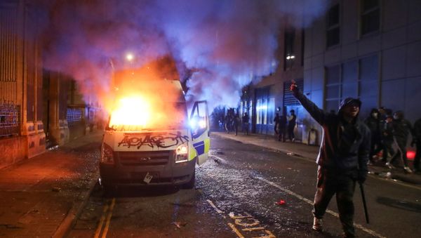 A demonstrator gestures near a burning police vehicle during a protest against a new proposed policing bill, in Bristol, Britain, March 21, 2021. A demonstrator gestures near a burning police vehicle during a protest against a new proposed policing bill, in Bristol, Britain, March 21, 2021. - Sputnik International