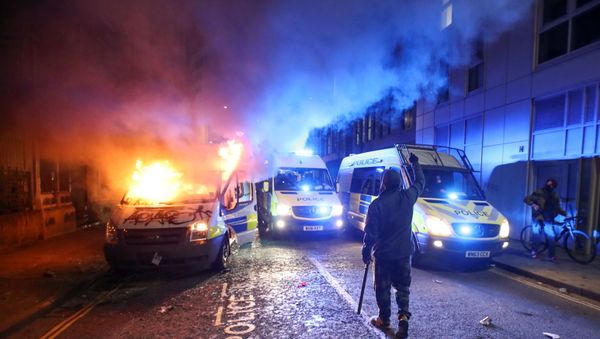 A demonstrator gestures near a burning police vehicle during a protest against a new proposed policing bill, in Bristol, Britain, March 21, 2021. - Sputnik International