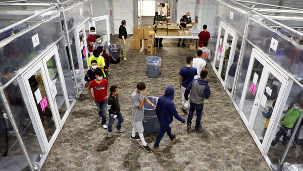 Migrants stand in line inside a temporary processing facility for migrants, including unaccompanied minors, in Donna, Texas, U.S. March 17, 2021 in this handout photo provided by the U.S. Customs and Border Protection agency. Picture taken March 17, 2021. - Sputnik International