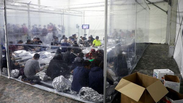 Migrants sit inside a temporary processing facility for migrants, including unaccompanied minors, in Donna, Texas, U.S. March 17, 2021 - Sputnik International