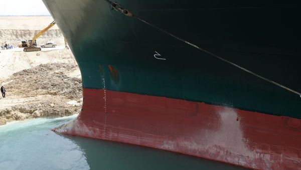 An excavator attempts to free stranded container ship Ever Given, one of the world's largest container ships, after it ran aground, in Suez Canal, Egypt March 25, 2021 - Sputnik International