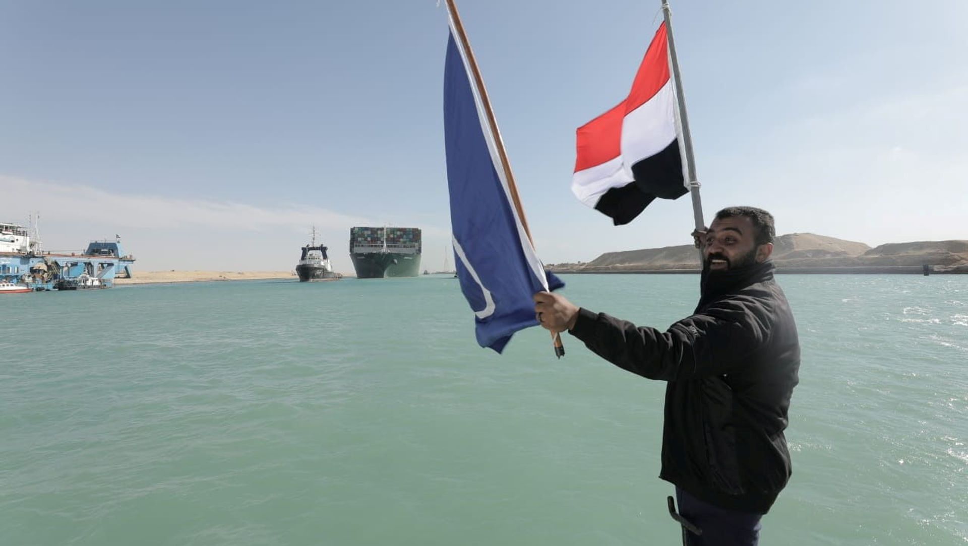 A man waves an Egyptian flag as the Ever Given, one of the world's largest container ships, is seen after it was fully floated in the Suez Canal, Egypt 29 March 2021. A man waves an Egyptian flag as the Ever Given, one of the world's largest container ships, is seen after it was fully floated in the Suez Canal, Egypt 29 March 2021. - Sputnik International, 1920, 30.03.2021