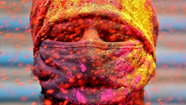 A man wearing a protective face mask reacts as colour powder is thrown towards him during Holi celebrations, amidst the spread of the coronavirus disease (COVID-19), in Chennai, India, March 29, 2021. - Sputnik International