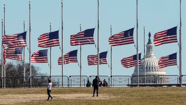 People walk past flags flying at half staff at the Washington Monument in memory of 500,000 deaths due to coronavirus disease (COVID-19) in Washington, U.S., February 24, 2021. - Sputnik International