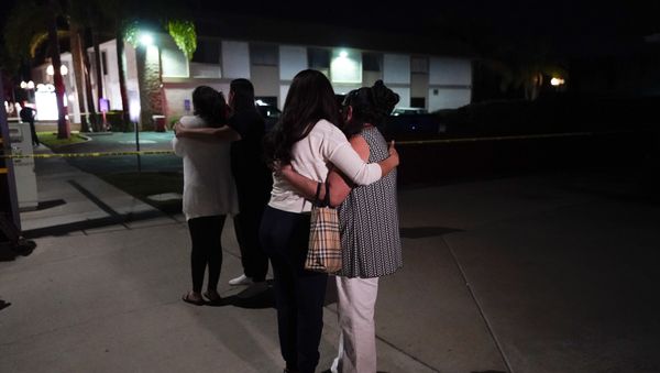Unidentified people comfort each other as they stand near a business building where a shooting occurred in Orange, Calif., Wednesday, March 31, 2021 - Sputnik International