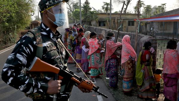 An armed policeman wearing a face shield stands guard as women wait in line to cast their votes outside a polling booth during the first phase of the West Bengal state election in Purulia district, India, March 27, 2021 An armed policeman wearing a face shield stands guard as women wait in line to cast their votes outside a polling booth during the first phase of the West Bengal state election in Purulia district, India, March 27, 2021 - Sputnik International