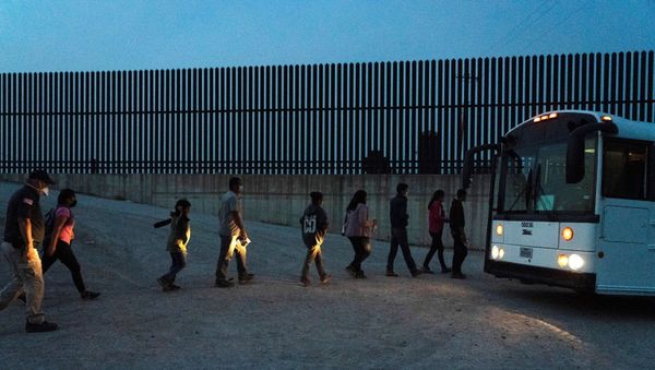 Asylum-seeking migrants' families queue to board a bus as they wait to be transported by the U.S. Border Patrols after crossing the Rio Grande river into the United States from Mexico in Penitas, Texas, U.S., March 26, 2021. - Sputnik International