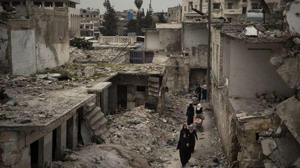 In this March 12, 2020 file photo, women walk in a neighborhood heavily damaged by airstrikes in Idlib, Syria. - Sputnik International