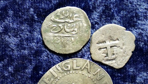 A 17th century Arabian silver coin, top, that research shows was struck in 1693 in Yemen, rests near an Oak Tree Shilling minted in 1652 by the Massachusetts Bay Colony, below, and a Spanish half real coin from 1727, right, on a table, in Warwick, R.I., Thursday, March 11, 2021. - Sputnik International