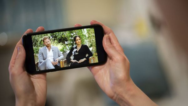 A man watches a phone screen showing an interview of Prince Harry and Meghan, The Duchess of Sussex, by Oprah Winfrey, in London Monday, March 8, 2021. - Sputnik International