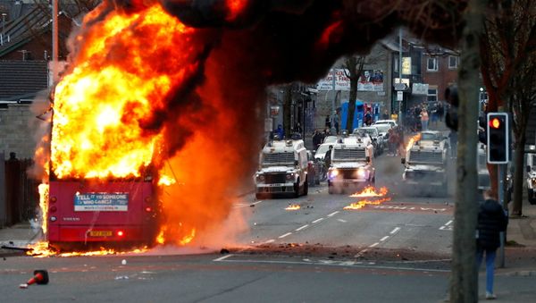Police vehicles are seen behind a hijacked bus burns on the Shankill Road as protests continue in Belfast, Northern Ireland, 7 April 2021 Police vehicles are seen behind a hijacked bus burns on the Shankill Road as protests continue in Belfast, Northern Ireland, 7 April 2021 - Sputnik International
