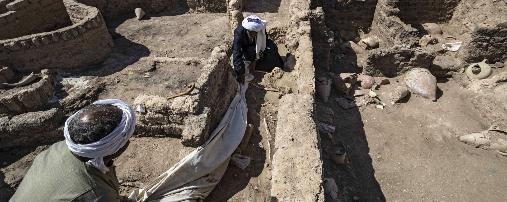 A picture taken on April 10, 2021, shows workers at the archaeological site of a 3000 year old city, dubbed The Rise of Aten, dating to the reign of Amenhotep III, uncovered by the Egyptian mission near Luxor. - Archaeologists have uncovered the remains of an ancient city in the desert outside Luxor that they say is the largest ever found in Egypt and dates back to a golden age of the pharaohs 3,000 years ago. Famed Egyptologist Zahi Hawass announced the discovery of the lost golden city, saying the site was uncovered near Luxor, home of the legendary Valley of the Kings. A picture taken on April 10, 2021, shows workers at the archaeological site of a 3000 year old city, dubbed The Rise of Aten, dating to the reign of Amenhotep III, uncovered by the Egyptian mission near Luxor. - Archaeologists have uncovered the remains of an ancient city in the desert outside Luxor that they say is the largest ever found in Egypt and dates back to a golden age of the pharaohs 3,000 years ago. Famed Egyptologist Zahi Hawass announced the discovery of the lost golden city, saying the site was uncovered near Luxor, home of the legendary Valley of the Kings. - Sputnik International, 1920, 11.04.2021