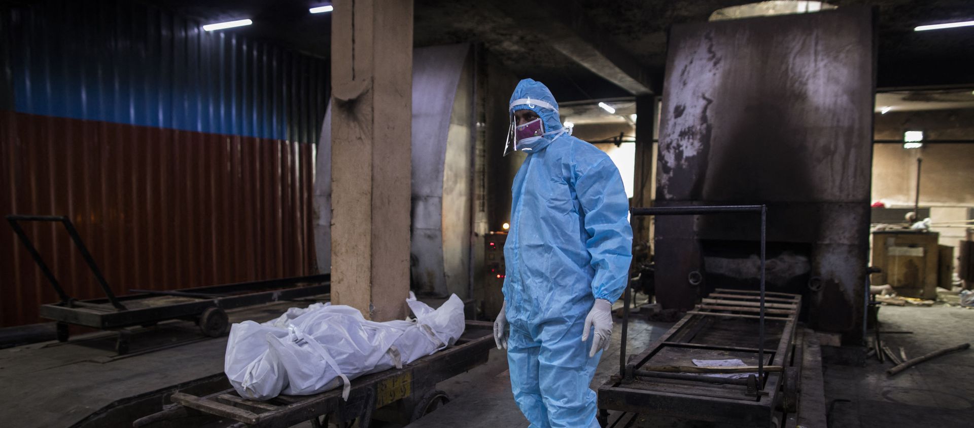 A relative wearing Personal Protective Equipment (PPE) stands next to the body of a person who died from the COVID-19 coronavirus before cremation in a furnace at the Nigambodh Ghat cremation ground, in New Delhi on 22 August 2020. - Sputnik International, 1920, 14.04.2021
