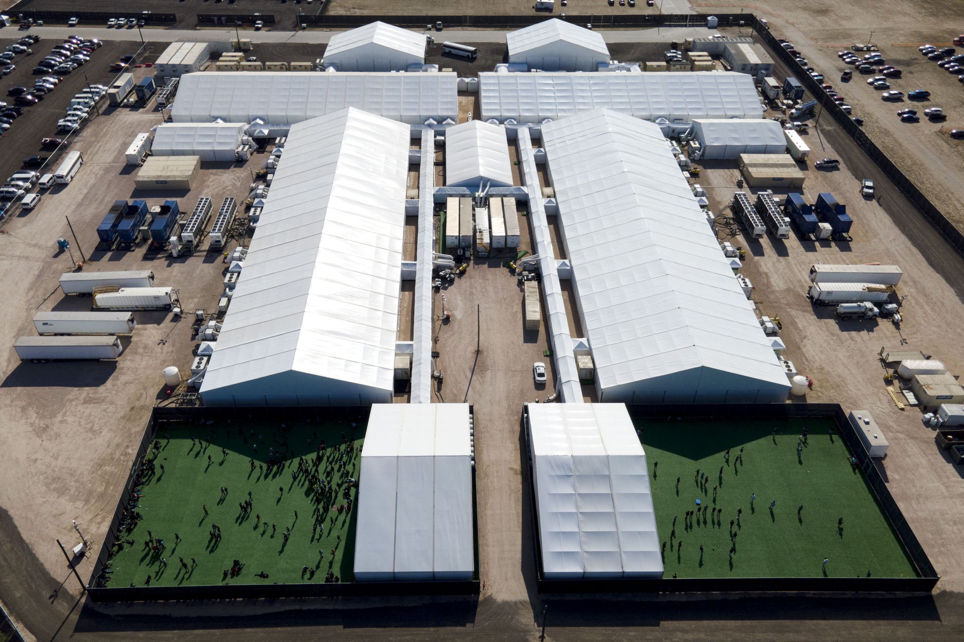 In this Friday, March 19, 2021, photo migrants are seen in a green area outside of a soft-sided detention center after they were taken into custody while trying to sneak into the U.S., in Donna, Texas. - Sputnik International, 1920, 07.09.2021