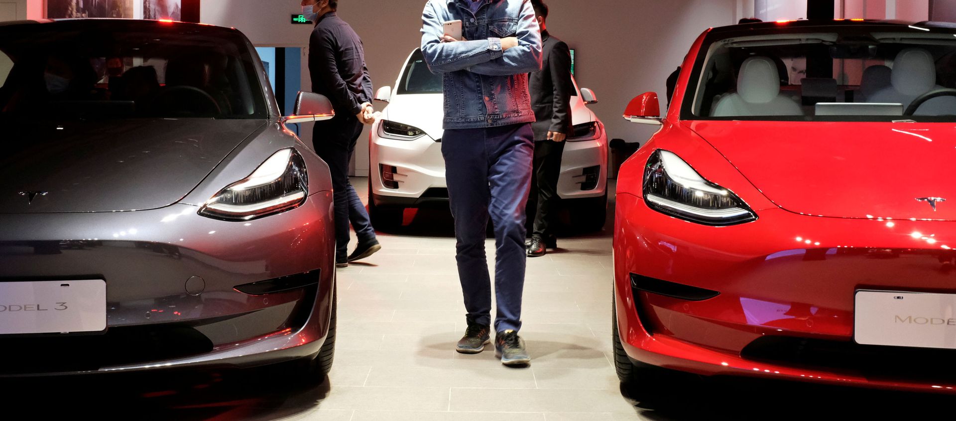 A man wearing a face mask following the coronavirus disease (COVID-19) outbreak walks by Tesla Model 3 sedans and Tesla Model X sport utility vehicle at a new Tesla showroom in Shanghai, China May 8, 2020. A man wearing a face mask following the coronavirus disease (COVID-19) outbreak walks by Tesla Model 3 sedans and Tesla Model X sport utility vehicle at a new Tesla showroom in Shanghai, China May 8, 2020. - Sputnik International, 1920, 19.04.2021
