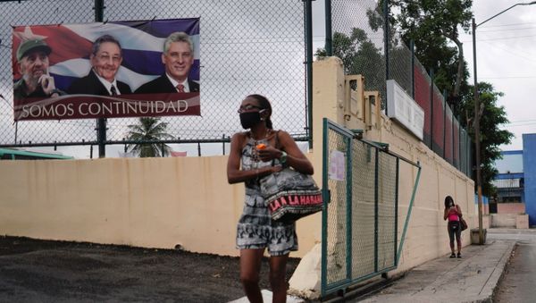 A woman passes by a poster displaying images of late Cuban President Fidel Castro, Cuba's First Secretary of the Communist Party and former President Raul Castro and Cuba's President Miguel Diaz Canel with a sign that reads: We are continuity, in Havana, Cuba, April 12, 2021 - Sputnik International