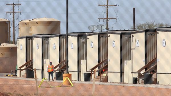 A worker is seen at the site of a former oil field workers camp which is being used as a temporary housing facility for migrant children in Midland County, Texas, U.S. April 8, 2021.  - Sputnik International