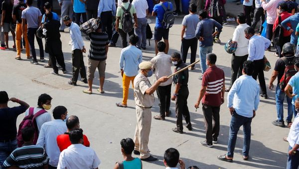 A police officer tries to control a crowd outside a wine store after Delhi government ordered a six-day lockdown to limit the spread of the coronavirus disease (COVID-19), in New Delhi, India April 19, 2021. - Sputnik International