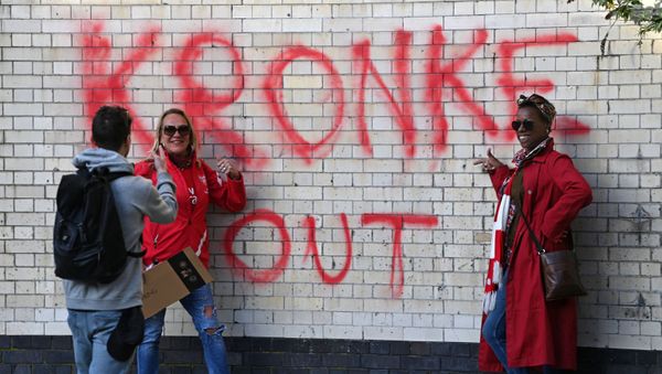 Two fans have their photograph taken beside a Kronke Out message sprayed on a wall as supporters protest against Arsenal's US owner Stan Kroenke, outside English Premier League club Arsenal's Emirates stadium in London on 23 April 2021, ahead of their game against Everton. Two fans have their photograph taken beside a Kronke Out message sprayed on a wall as supporters protest against Arsenal's US owner Stan Kroenke, outside English Premier League club Arsenal's Emirates stadium in London on 23 April 2021, ahead of their game against Everton. - Sputnik International