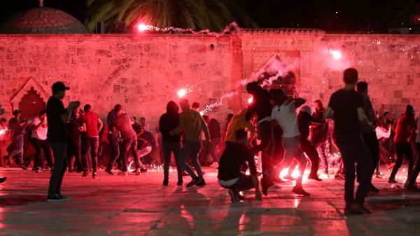 Palestinians react as Israeli police fire stun grenades during clashes at the compound that houses Al-Aqsa Mosque, known to Muslims as Noble Sanctuary and to Jews as Temple Mount, amid tension over the possible eviction of several Palestinian families from homes on land claimed by Jewish settlers in the Sheikh Jarrah neighbourhood, in Jerusalem's Old City, May 7, 2021 - Sputnik International