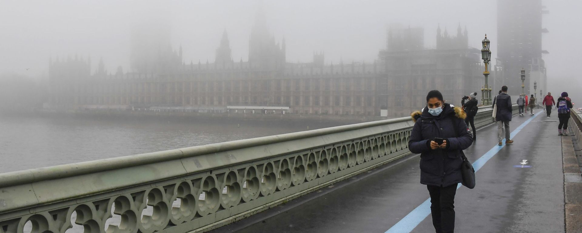 People wearing face masks, walk over Westminster Bridge with the Houses of Parliament shrouded by fog, in London, Tuesday, Dec. 8, 2020 People wearing face masks, walk over Westminster Bridge with the Houses of Parliament shrouded by fog, in London, Tuesday, Dec. 8, 2020 - Sputnik International, 1920, 21.10.2021